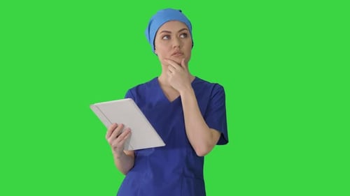 Young Woman Doctor or Nurse in Scrubs Using a Touchscreen Computer While Walking on a Green Screen