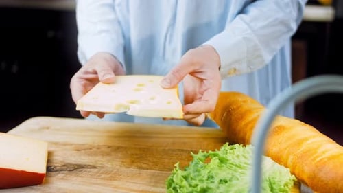 Woman Preparing Sandwich with Cheese and Baguette