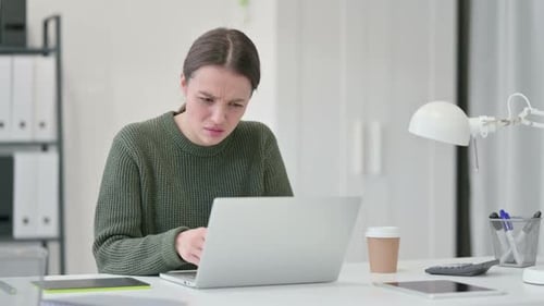 Young Adult Woman Looking Perplexed at Laptop
