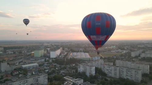 Colorful Hot Air Balloons Flying Over Green Park and Buildings in Small European City at Summer