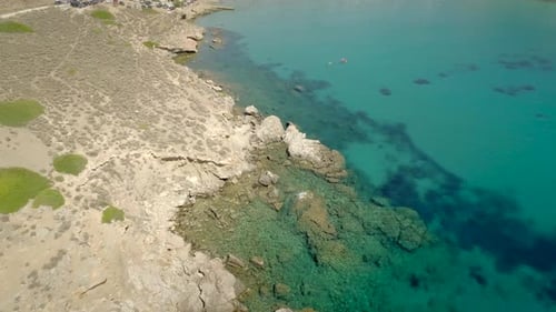Aerial view of beach shore with rocks and very calm water in Greece.