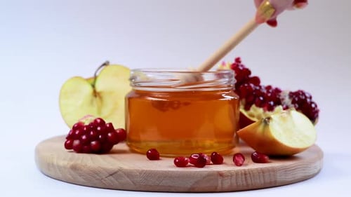 Honey Dripping in Jar with Apples and Pomegranate