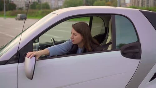 Woman Adjusts Side Mirror in Compact Car