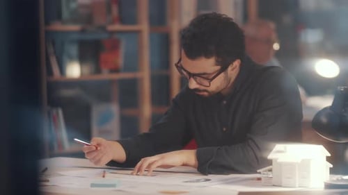 Young Thoughtful Arab Architect Working on Floor Plan in Office