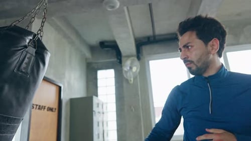 4K Caucasian man athletic do kickboxing workout and punching boxing bag at gym.
