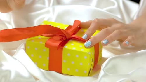 Woman Unties Ribbon on Polka Dot Gift Box