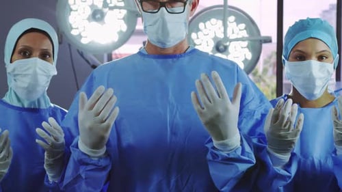 Front view of surgeons gesturing while standing in operating room at hospital