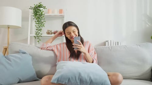 Woman Using Smartphone on Sofa at Home