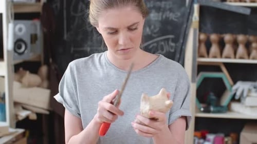 Woman Carving Wood Sculpture in Workshop