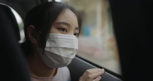 Asian Girl In Car Wearing A Medical Mask During Pandemic Of Coronavirus Covid-19