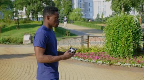 Man Uses Phone While Walking in Urban Park