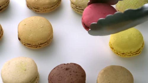 Colorful Macarons Arranged and Placed with Tongs