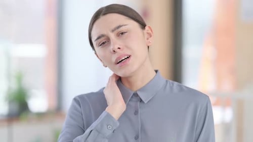 Woman Massaging Sore Neck Muscles in Office