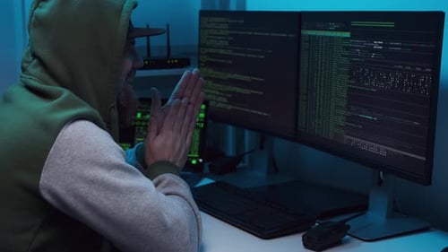 Aufgeregter Hacker in Maske reibt sich die Hände, bevor er versucht, das System zu hacken oder mit einem Virus zu infizieren