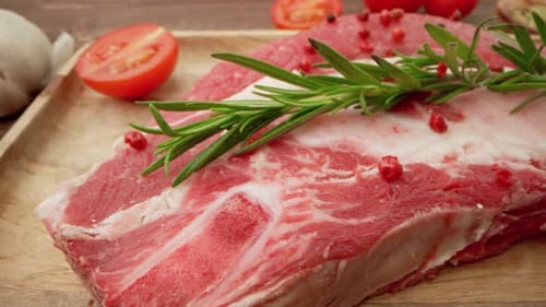 Frische rohe Fleischsteaks auf Holzbrett mit Gewürzen aus nächster Nähe