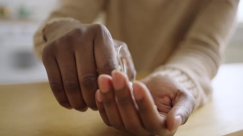 Person pouring pills into hand for daily medicine