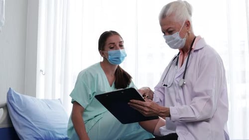 Doctor Discussing Medical Records With Patient in Hospital