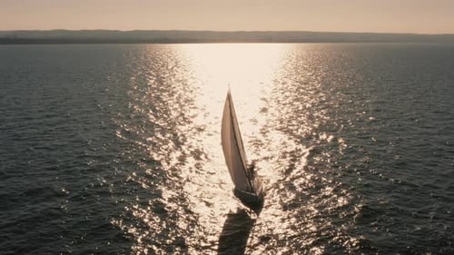 Evening Seascape with a Yacht with White Sails in the Open Sea Aerial View