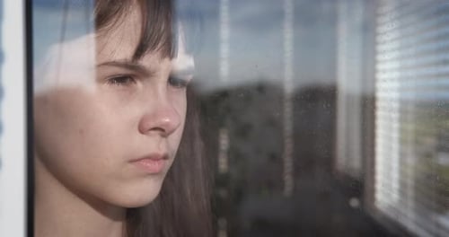 Pensive Girl Stares Out Rainy Window, Close-Up