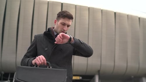 Businessman looking at his watch and walking