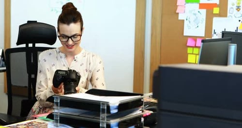 Young Woman Holding SLR Camera in Modern Office