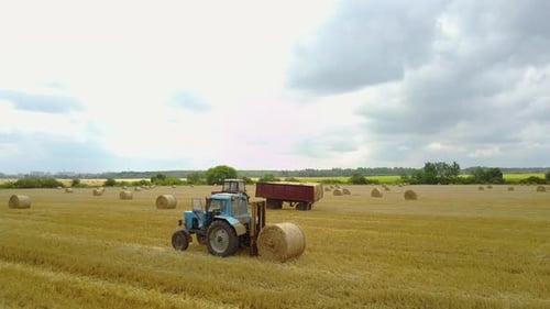 Tractors and Hay Bales in Golden Agricultural Field