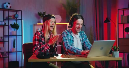 Blondie apoya a su novio barbudo, activo y emocionado, que juega Vídeo en una computadora portátil