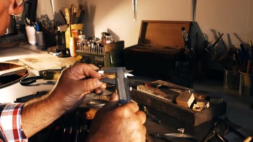 Craftsman Measuring Jewelry with Caliper in Workshop