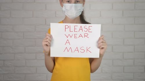 Child Holds Sign Asking to Wear a Mask