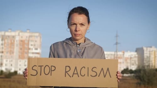 Woman Holding Stop Racism Sign in Urban Setting