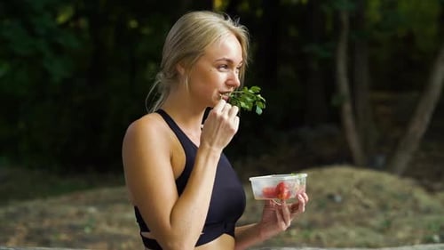 Fit woman having healthy snack outside