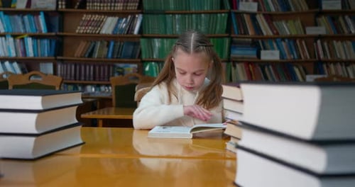 A Little Girl Is Studying Among the Many Books in the Reading Room in the Library.
