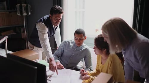 Group of people looking at blueprint in the office