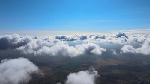 Luftaufnahme aus dem Flugzeugfenster in großer Höhe der Erde, bedeckt mit weißen, geschwollenen Cumuluswolken
