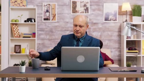 Man Working on Laptop at Desk with Gray Hair