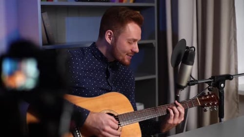 Man Plays Guitar and Sings in Studio Setting
