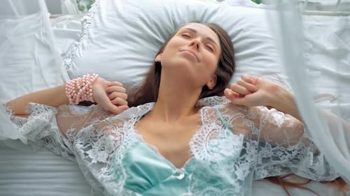Attractive Woman Lying in White Bed Stretching