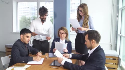 Group of Young Businessman at the Negotiating Table in the Office. Colleagues Look Through Documents