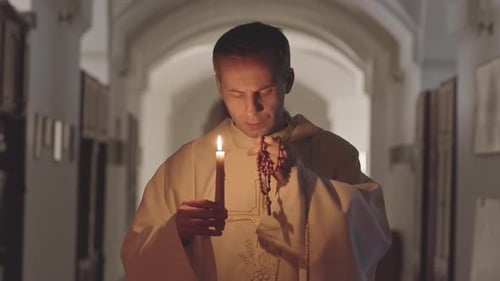 Man Holding Candle and Rosary Beads in Church
