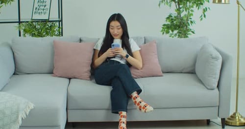 Woman Relaxing on Couch Using Smartphone
