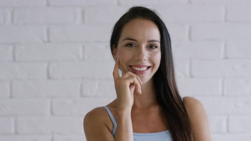 Smiling Woman Posing in Front of White Brick