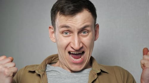 Angry Man Gets Irritated Clenching Fists on Grey Background