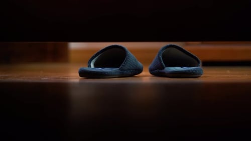 Feet Putting on Slippers Under Bed at Home