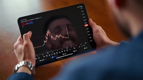Man Holding Tablet Displaying Cryptocurrency Data Indoors
