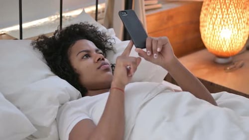 Woman Using Mobile Phone Lying in Bed