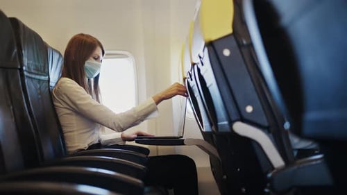 Woman with Mask Working on Laptop in Airplane