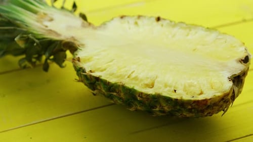 Halved Pineapple Sits on a Yellow Surface