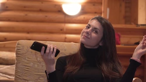 Close View of Woman with Remote Control in Hand Playing with Her Hair