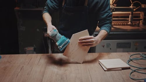 Closeup of a Woodworker's Hand Sanding Wood Details with a Grinder in His Workshop