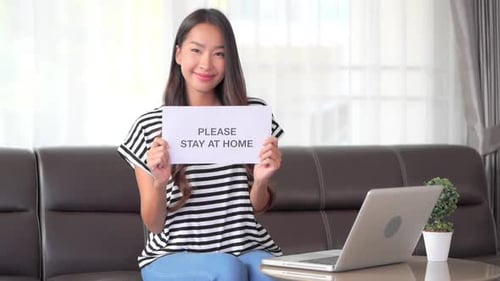 Woman Holds Stay at Home Sign on Couch
